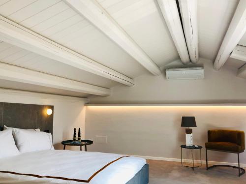 a bedroom with a large bed and a chair at Alma White Suite in Siracusa