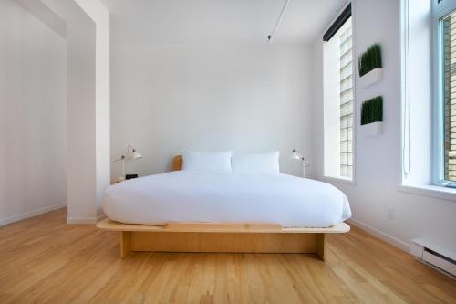 a white bedroom with a white bed and a window at Les Lofts St-Roch - Par Les Lofts Vieux-Québec in Quebec City