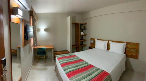 Schlafzimmer mit einem Bett und einem Schreibtisch mit einem TV in der Unterkunft Meu Hotel Boituva in Boituva