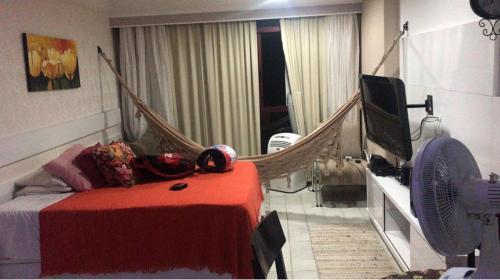 um quarto com uma cama de rede de descanso e uma televisão em flat apt mobiliado beira mar no Recife