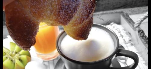 a piece of bread is hanging over a cup of coffee at Borgo Albador Rooms in Posada