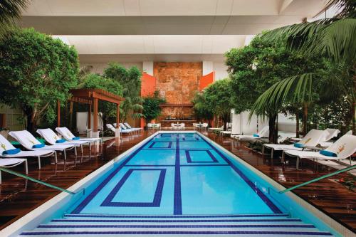 a swimming pool in a hotel lobby with chairs and trees at MGM Tower at Borgata in Atlantic City