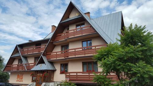 een groot huis met een schilddak bij Miś Pokoje Gościnne in Bukowina Tatrzańska