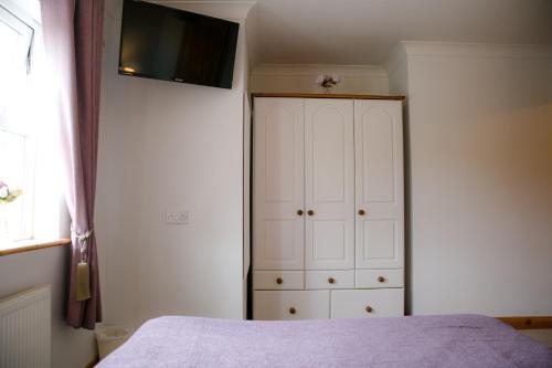 a bedroom with a bed and a white cabinet at Farmleigh House, in Donegal