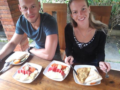 a man and a woman sitting at a table with food at Nami House in Ubud