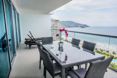 a dining table and chairs on a balcony with the ocean at PENINISULA ViSTA AL MAR BY ENNA INN IXTAPA in Ixtapa