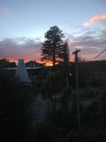 a sunset view of a house with a tree at Waitomo Caves Guest Lodge in Waitomo Caves