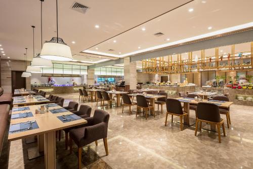 a dining room with tables and chairs in a restaurant at Millennium Resort Wuyishan in Wuyishan