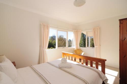 a bedroom with a bed and two windows at Bimbadeen Comfortable country styled house in Kangaroo Valley