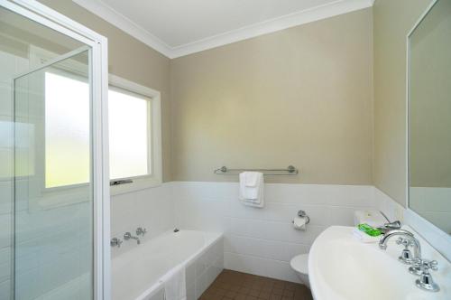 a bathroom with a tub and a toilet and a sink at Bimbadeen Comfortable country styled house in Kangaroo Valley