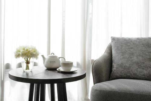 a table with a tea pot and a chair next to a window at Sivatel Bangkok Hotel in Bangkok