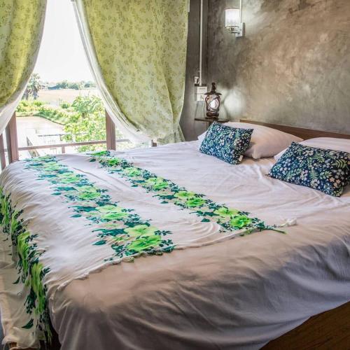 a bed with blue flowers on it with a window at Falik Farm Stay in Phra Nakhon Si Ayutthaya