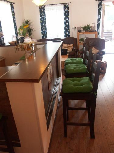 a kitchen with a counter with green cushioned chairs at Penzion Bobešova bouda in Železná Ruda