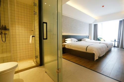 a bedroom with a bed and a bathroom with a shower at Hangzhou Yuqi Hotel - West Lake Leifeng Tower Branch in Hangzhou