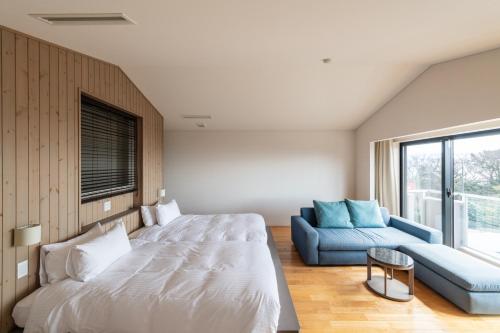 a bedroom with a large bed and a blue couch at the salon 伊豆高原 Hotels & Resort in Ito