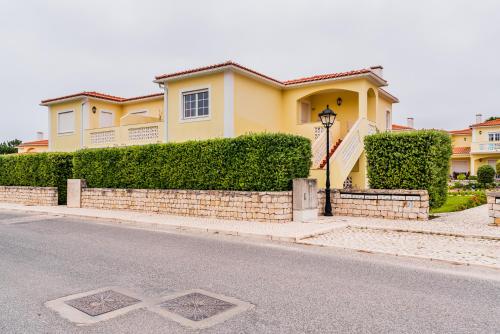 a yellow house on the side of a street at Burgo Dom Afonso V Golf & Beach Resort in Casal da Lagoa Seca