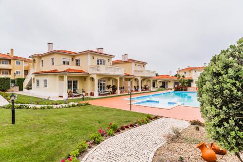 una casa grande con un patio con piscina en Burgo Dom Afonso V Golf & Beach Resort, en Casal da Lagoa Seca