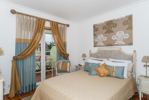a bedroom with a bed with blue and gold pillows at Burgo Dom Afonso V Golf & Beach Resort in Casal da Lagoa Seca
