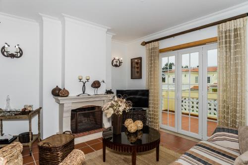 a living room with a fireplace and a tv at Burgo Dom Afonso V Golf & Beach Resort in Casal da Lagoa Seca