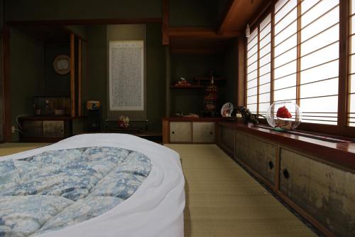 a bedroom with a bed in a room with windows at Maidohaya Fukutatei in Takaoka