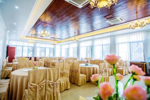a banquet hall with tables and chairs and chandeliers at 36Manor International Sport Hotel in Vientiane