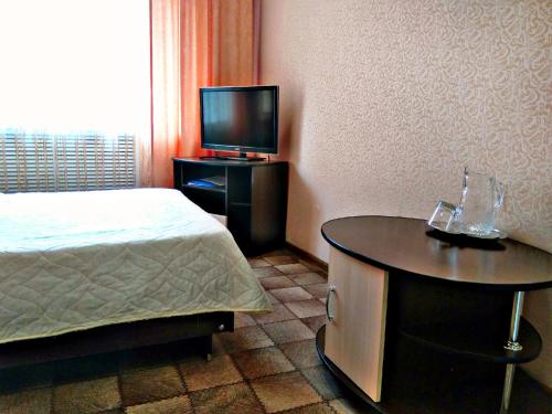 a bedroom with a bed and a table with a tv at Hotel Kolos in Barnaul