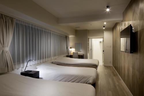 a hotel room with a large bed and a large window at Shinjuku City Hotel N.U.T.S Tokyo in Tokyo