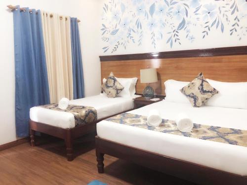 a bedroom with two beds and a table with two chairs at Blue Waters Inn Coron Palawan in Coron