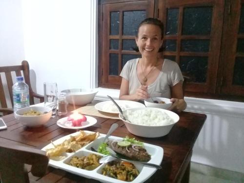 a woman sitting at a table with a plate of food at Green Edge Residences in Dambulla