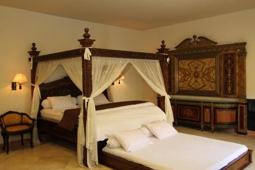 a bedroom with two beds and a canopy bed at griya desa hotel & pool in Yogyakarta