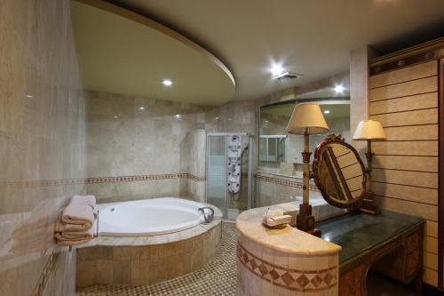 日惹griya desa hotel & pool的带浴缸和镜子的大浴室