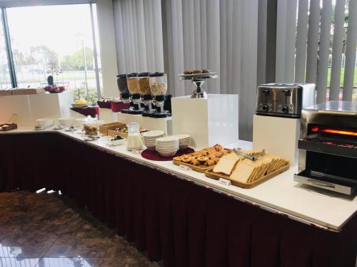 a buffet with food on a counter in a room at Auckland Airport Kiwi Hotel in Auckland