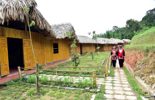 two people standing in front of a building at Dao Homestay in Hoàng Su Phì