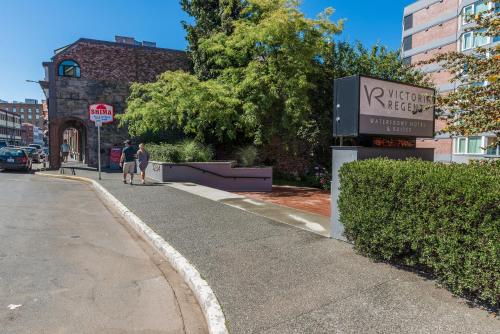 two people walking down a sidewalk next to a street at Victoria Regent Waterfront Hotel & Suites in Victoria