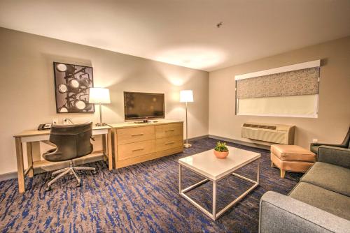 a hotel room with a couch and a desk and a television at Best Western Plus Media Center Inn & Suites in Burbank