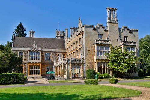 a large stone building with a green lawn in front at Orton Hall Hotel & Spa in Peterborough