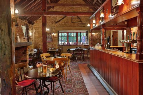 a restaurant with tables and chairs and a bar at Orton Hall Hotel & Spa in Peterborough