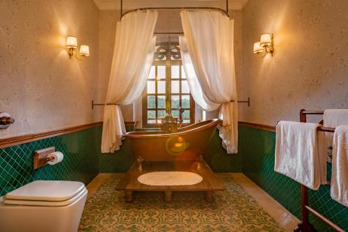 a bathroom with a tub and a toilet and a window at Amrapali-House of Grace in Bambolim