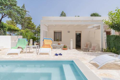 a pool with chairs and a table and a house at Palms Villa in Scopello