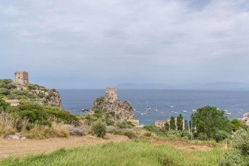 a castle on top of a hill next to the ocean at Palms Villa in Scopello