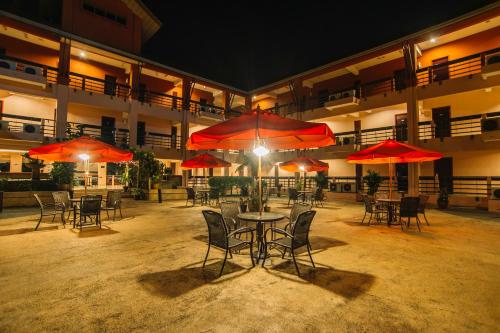 a patio with tables and chairs with red umbrellas at Hotel Seri Malaysia Melaka in Melaka