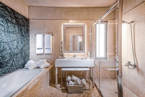 a bathroom with a sink and a bath tub and a sink at Blue Bay Resort Hotel in Agia Pelagia