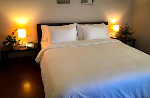 1 dormitorio con 1 cama blanca y 2 lámparas en Siam Bright Suite, en Bangkok