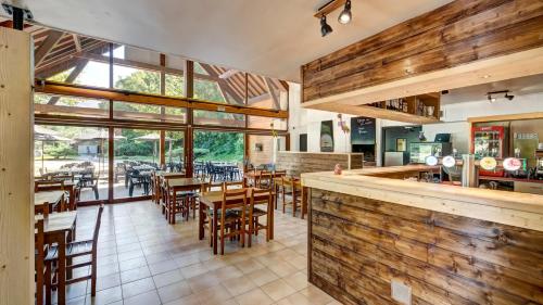 un restaurant avec des murs en bois, des tables et des chaises dans l'établissement Vacancéole - Le Village des Oiseaux, à Motz