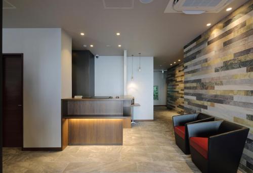 a lobby with two black chairs and a counter at HOTEL PROMOTE HIROSHIMA in Hiroshima