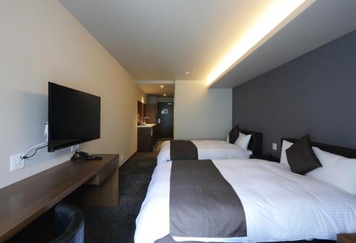 a hotel room with two beds and a flat screen tv at HOTEL PROMOTE HIROSHIMA in Hiroshima