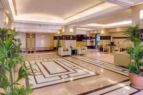 a lobby with chairs and plants in a building at Novel Hotel City Center in Abu Dhabi