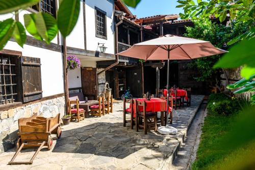a patio with tables and chairs and an umbrella at Banskovilla Zlateva House in Bansko