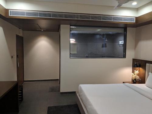 a bedroom with a bed and a window at Hotel Avaante Ahmedabad Formerly known as The Orchid Hotel in Ahmedabad