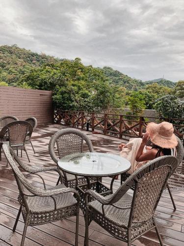 a woman sitting on a deck talking on a cell phone at HiONE Holiday Hotel in Shenkeng